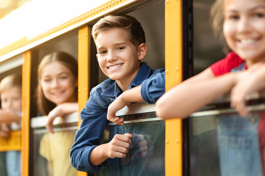 Excited school children peeping from the school bus window before a field trip.